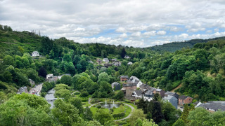 Panoramisch uitzicht op groene heuvels, rivier, huizen en bomen bij Camping la Roche in Limburg, België.