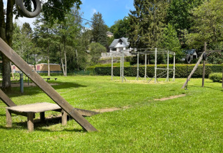 Parco giochi con teleferica e prato verde al Camping la Roche, parco vacanze nel Limburgo, Belgio, in giornata soleggiata.