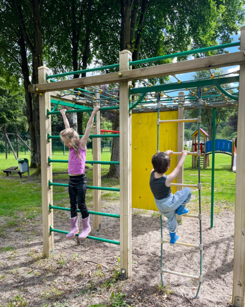 Bambini che giocano su una struttura da arrampicata al Camping la Roche, Limburg, Belgio, tra gli alberi.