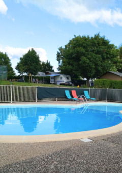 Round swimming pool with lounging chairs at Camping du Lac holiday park, Grand Est, France, on sunny day.