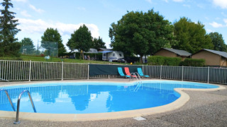 Round swimming pool with lounging chairs at Camping du Lac holiday park, Grand Est, France, on sunny day.