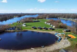 Vista aerea di Camping de Kleine Wielen in Frisia, Paesi Bassi, con lago, scivolo e bungalow.