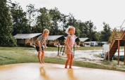 Due bambini giocano su un grande tappeto elastico al Camping de Kleine Wielen, parco vacanze in Frisia, Paesi Bassi.