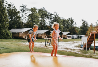 Due bambini giocano su un grande tappeto elastico al Camping de Kleine Wielen, parco vacanze in Frisia, Paesi Bassi.