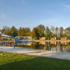 View of a lakeside playground with water slide and cabins at Camping de Kleine Wielen in Friesland, Netherlands.