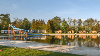 Naturskønt udsyn over sø og lejrhytter med vandrutsjebane på Camping de Kleine Wielen i Friesland, Holland.