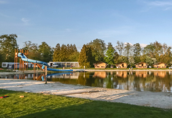 Panorama sul lago con scivolo d’acqua e bungalow a Camping de Kleine Wielen, Friesland, Paesi Bassi.