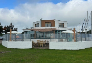 Buitenterras met tafels en parasols bij Minicamping Marina Warns, vakantiepark in Friesland, Nederland.