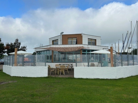 Outdoor seating area with tables and umbrellas at Minicamping Marina Warns, Friesland holiday park, Netherlands.