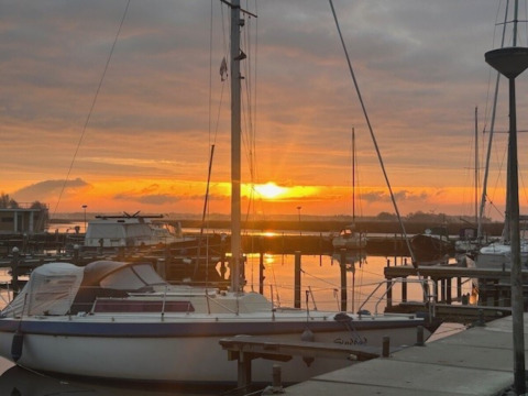 Sonnenuntergang über dem Jachthafen bei Minicamping Marina Warns in Friesland, Niederlande, mit Booten.