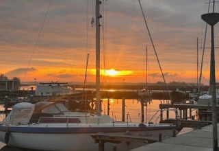 Solnedgang over lystbådehavnen ved Minicamping Marina Warns i Friesland, Holland, med både fortøjet.