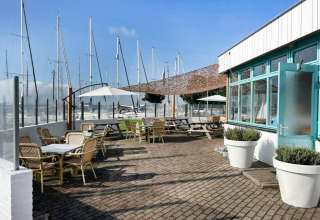 Terrasse extérieure avec tables et chaises à Minicamping Marina Warns, Friesland, vue sur le port de plaisance.