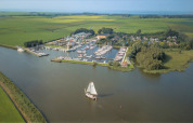 Luftfoto af Minicamping Marina Warns feriepark med bådehavn i Friesland, Holland, omgivet af marker.
