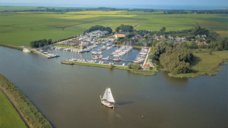 Luftfoto af Minicamping Marina Warns feriepark med bådehavn i Friesland, Holland, omgivet af marker.