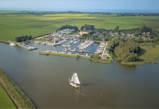 Luftfoto af Minicamping Marina Warns feriepark med bådehavn i Friesland, Holland, omgivet af marker.