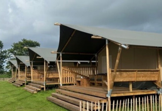 Rangée de tentes safari sur terrasses en bois à Minicamping Marina Warns, parc de vacances en Frise, Pays-Bas.