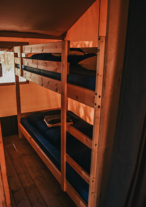 Stapelbedden in een safaritent met sanitaire voorzieningen op Camping Lucherino in Italië, binnenaanzicht.