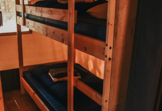 Køjesenge i et safari-telt med sanitære faciliteter på Camping Lucherino i Italien, set indefra.