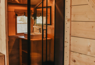Baño moderno con ducha acristalada en tienda safari con baño privado en Camping Lucherino, Italia.