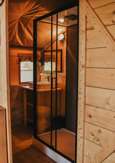 Modernes Badezimmer mit Glasduschkabine in einem Safari-Zelt mit eigenem Bad auf Camping Lucherino, Italien.