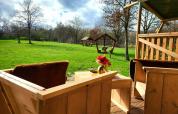 Vista desde la terraza de madera de una tienda safari con sanitarios en Jocomo Parc, Bélgica, campo verde.