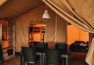Indretning af Safari Tent Valley ved Camping Lucherino i Italien med spisebord, stole og soveområde.