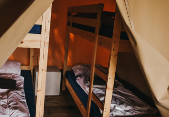 Interior view of Safari Tent Valley at Camping Lucherino in Italy, featuring bunk beds and wooden flooring.