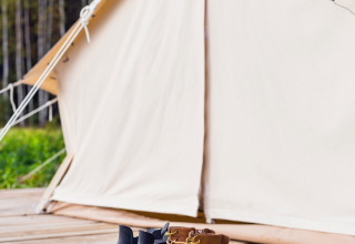 Støvler og gummistøvler foran et Belltent på Camping Lucherino, Italien, omgivet af skov.