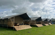 Safari telte på Minicamping Marina Warns i Holland, med træterrasser og grøn græsplæne under en overskyet himmel.