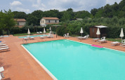 Piscina all'aperto con lettini e ombrelloni al Camping Monti del Sole, parco vacanze in Umbria, Italia.