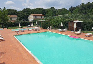 Udendørs swimmingpool med liggestole og parasoller ved Camping Monti del Sole, feriepark i Umbrien, Italien.