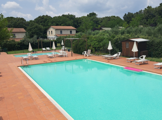Buitenzwembad met ligstoelen en parasols bij Camping Monti del Sole, vakantiepark in Umbrië, Italië.