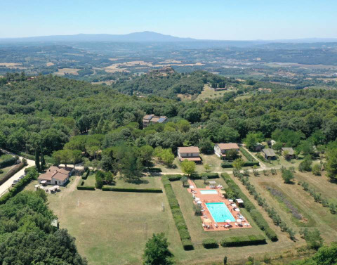Aerial view of Camping Monti del Sole in Umbria, Italy, showing pool, holiday cottages, and green countryside.