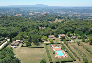 Aerial view of Camping Monti del Sole in Umbria, Italy, showing pool, holiday cottages, and green countryside.