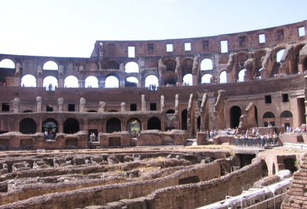 Vue intérieure du Colisée, célèbre amphithéâtre romain antique, avec visiteurs et ruines visibles.