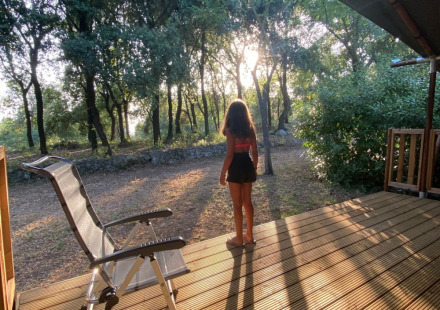 Persoon op houten terras in zonlicht bij Camping Monti del Sole, een vakantiepark in Umbrië, Italië.