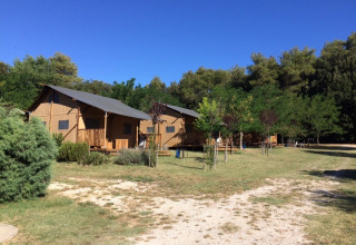 Camping Monti del Sole in Umbrië, Italië met glamping tenten, grasvelden, bomen en een heldere blauwe lucht.