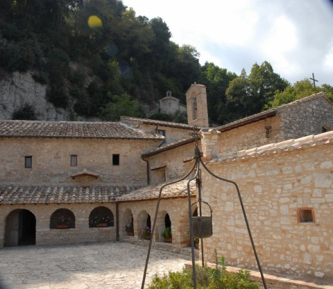 Monastero in pietra con archi nei pressi di Narni, Umbria, Italia, immerso tra colline e vegetazione.