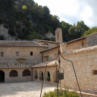 Monastère en pierre avec arches près de Narni, Ombrie, Italie, entouré de collines verdoyantes et forêt.