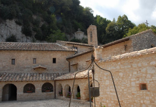 Monastère en pierre avec arches près de Narni, Ombrie, Italie, entouré de collines verdoyantes et forêt.