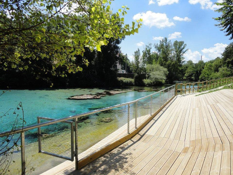 View of the clear blue water at Camping Monti del Sole in Umbria, Italy, with a wooden boardwalk.