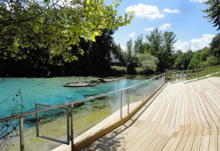 View of the clear blue water at Camping Monti del Sole in Umbria, Italy, with a wooden boardwalk.