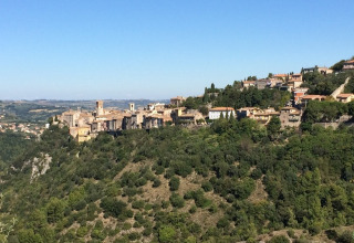 Udsigt over Narni, en historisk by i Umbrien, Italien, omgivet af grønne bakker under en klar himmel.