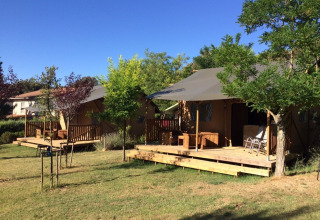 Glamping tents with wooden decks at Camping Monti del Sole, a holiday park in Umbria, Italy on a sunny day.