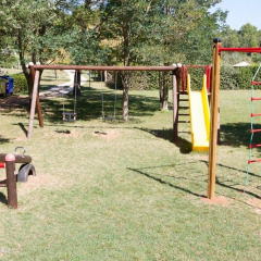 Parco giochi al Camping Monti del Sole in Umbria, Italia, con altalene, scivolo e scala da arrampicata.