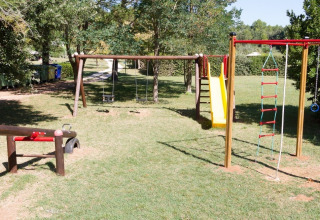 Playground at Camping Monti del Sole in Umbria, Italy, with swings, slide, and climbing ladder on grass.