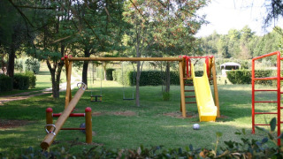 Aire de jeux avec balançoire, toboggan jaune et balancier au Camping Monti del Sole en Ombrie, Italie.