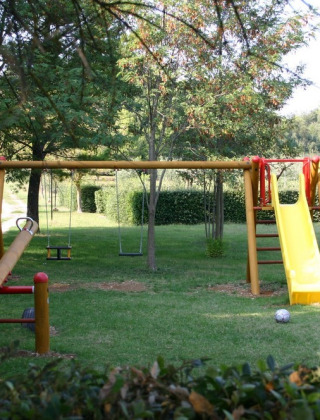 Aire de jeux avec balançoire, toboggan jaune et balancier au Camping Monti del Sole en Ombrie, Italie.