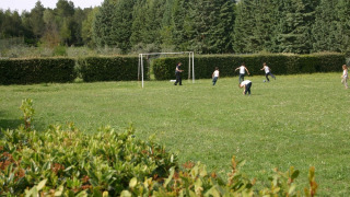 Des enfants jouent au football sur une pelouse entourée d’arbres à Camping Monti del Sole en Ombrie, Italie.