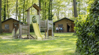 Parco giochi e tende safari al Recreation Park Den Blanken, Paesi Bassi, con persone sedute sullo sfondo.